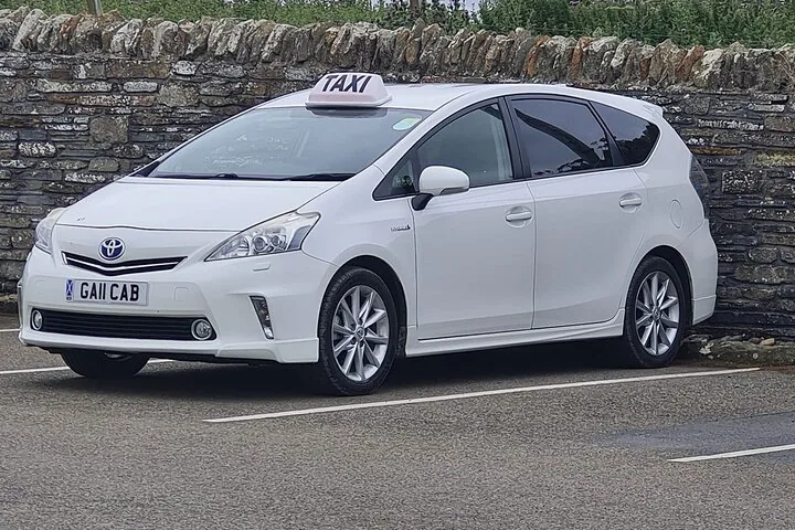 Weißes Toyota Prius Taxi geparkt an einer Steinmauer