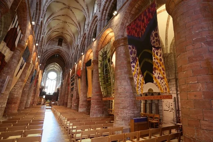 Interno di una grande cattedrale con enormi pilastri in pietra e stendardi