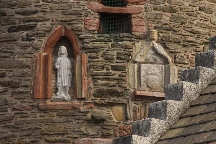 Primo piano di una torre in pietra con figure scolpite e dettagli