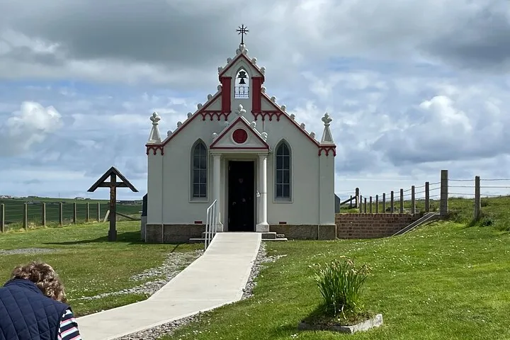 Kleine weiße Kapelle mit roten Verzierungen und einem Holzkreuz
