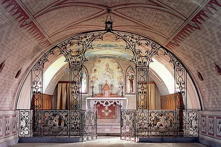 Innenraum einer Kapelle mit verziertem Metallgitter und bemalter Decke